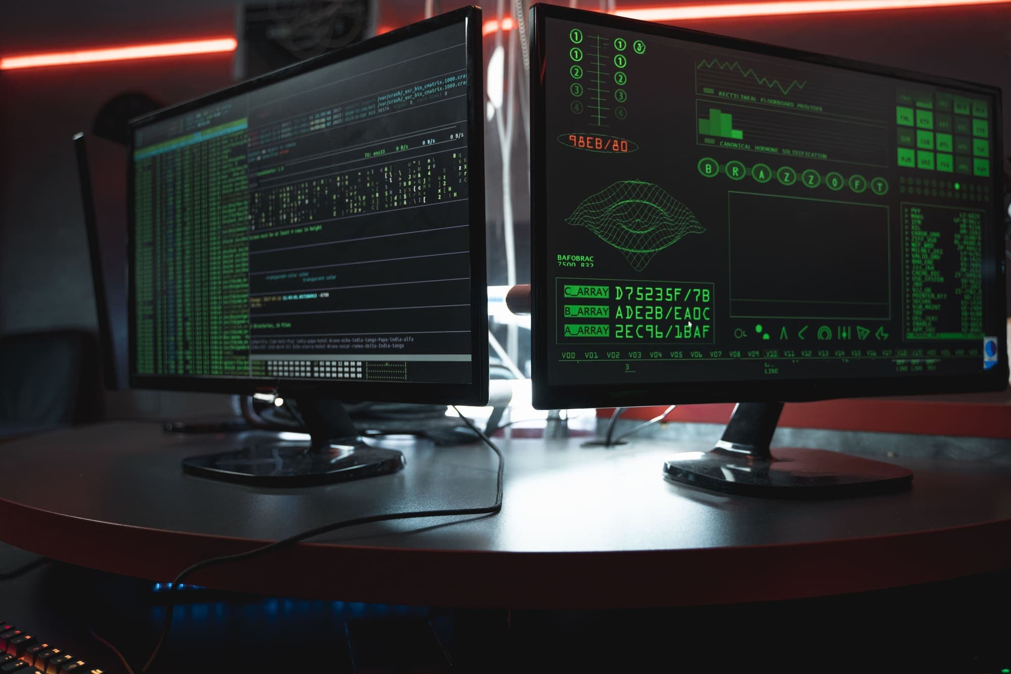 Two monitors showing terminal output and a diagnostic display in a dim room.