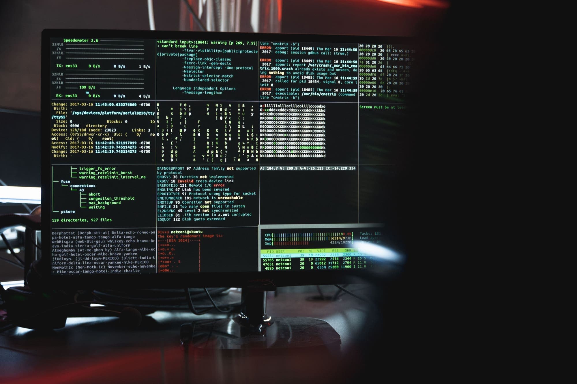 A monitor of terminal windows with logs and warnings, in a dark room.