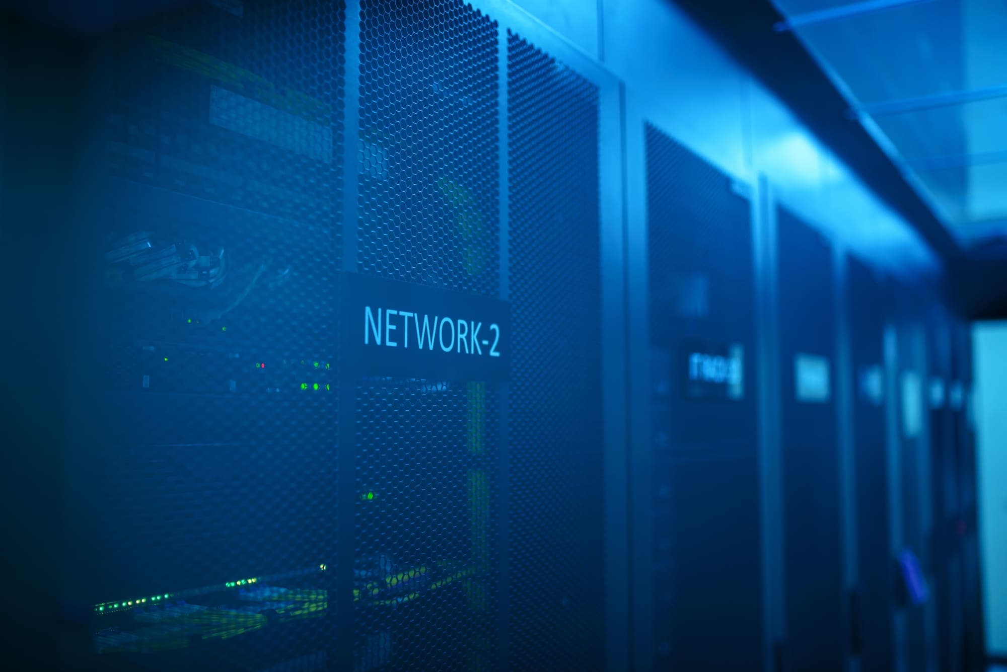 Server racks in a dim data center, one door labelled NETWORK-2.